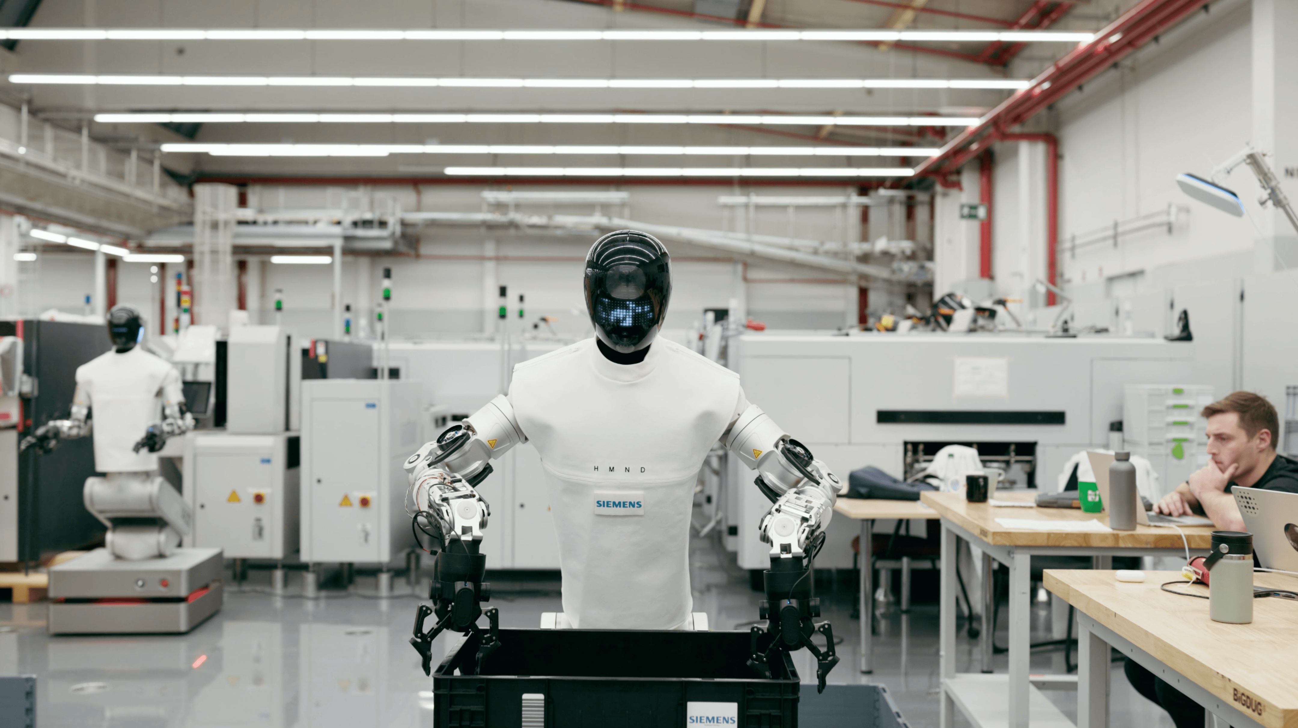Robot HMND 01 Alpha manipuluje s prepravkou v priemyselnej hale Siemens.